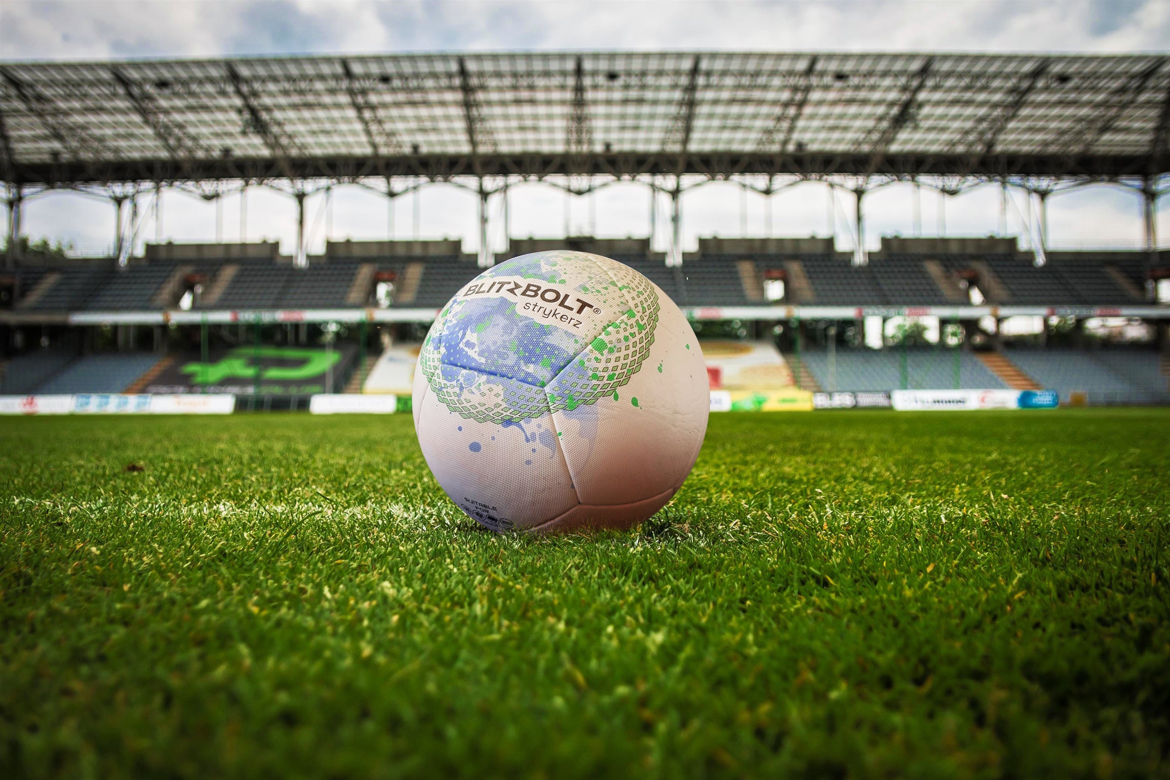 A BlitzBolt soccer ball on the grass in a stadium.